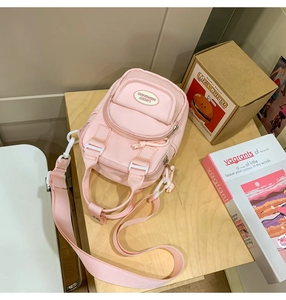 Detail view of pink nylon mini backpack with multiple zipper pockets and logo