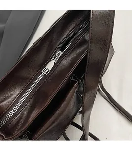 Detail of smooth silver zipper and lychee leather texture on dark brown shoulder bag