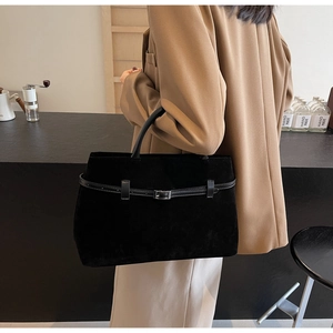 Detail of black suede tote bag with belt buckle on a warm lifestyle background