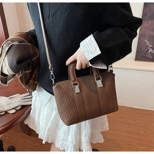 Détail d'un sac seau rétro marron foncé avec texture plissée et boucles argentées