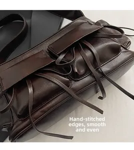 Detail of dark brown leather handbag featuring stitching and shiny oil-wax texture