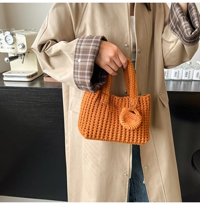 Macro view of handmade chunky orange knit bucket bag with engraved wooden tag