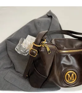 Detail of dark brown vintage tote bag with gold M logo and adjustable shoulder strap
