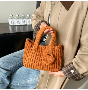 Detail of rust orange knit handbag featuring thick crochet texture and handmade charm