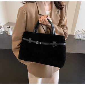 Detailed close-up of matte black suede tote bag featuring silver buckle and leather handles