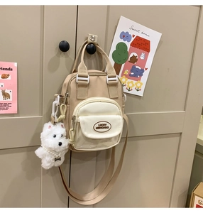 Close-up of mini patchwork crossbody bag with plush puppy pendant and brand logo