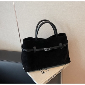 Close-up of black matte suede tote bag featuring slim leather straps and metal buckles