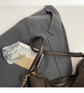 Close-up of brown tote bag leather texture with golden zipper on a grey blazer