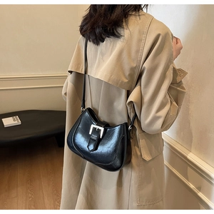 Model view of black leather underarm bag with silver square buckle and sleek curved design