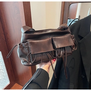 Detail of dark brown retro shoulder bag featuring dual flap pockets and leather drawstring