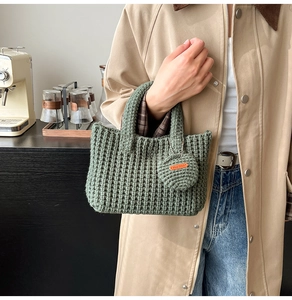 Detail of green knit tote bag with vertical crochet texture and Hand Made leather tag