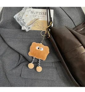 Detail of a cute toast plush charm with striped legs hanging on a brown leather tote bag
