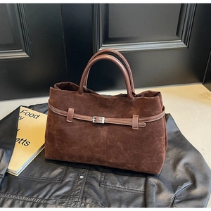 Detail of dark brown suede tote bag featuring a leather strap and silver buckle