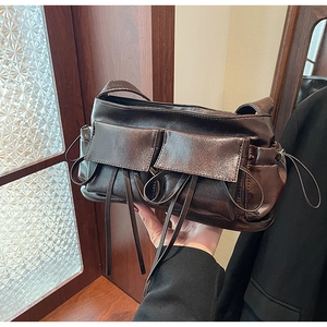 Close-up of a dark brown bow-knot pleated bowling bag with utilitarian flap pockets