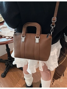 Brown retro bucket bag with vertical stripe embossing and silver hardware on a model