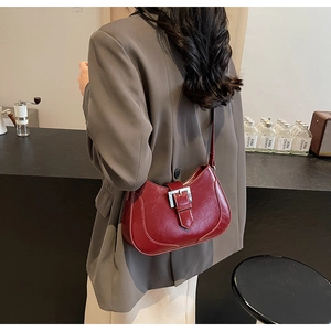 Close-up of retro red leather underarm bag featuring a metallic silver buckle detail