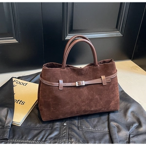 Detail of dark brown suede tote bag with silver buckle strap and textured finish