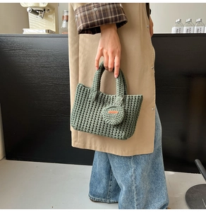 Detailed macro view of dark green hand-knitted bag with brown leather handmade tag label