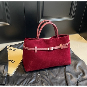 Detailed macro view of dark red velvet tote bag with leather belt and silver buckle