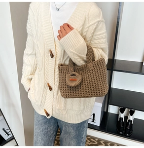 Close-up of brown knit bucket bag with Hand Made heart charm and thick woven texture