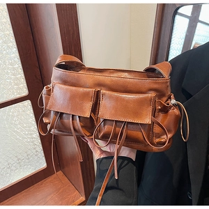 Detailed view of caramel PU leather shoulder bag with decorative drawstrings and front pockets