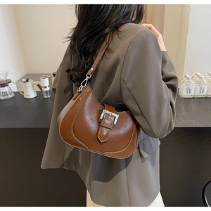 Close-up of brown faux leather shoulder bag with white contrast stitching and silver buckle