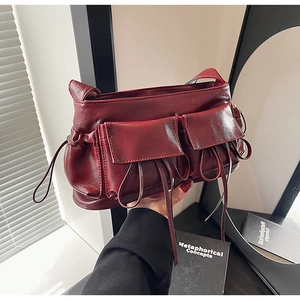 Close-up of wine red vintage handbag with front pockets and long tassel details