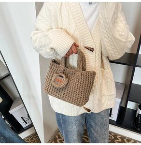 Close-up of khaki knit bucket bag featuring a Hand Made charm and chunky woven texture