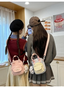 Close-up of mini canvas crossbody bags with plush dog charms in a cozy cafe setting