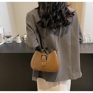 Caramel crescent shoulder bag with silver buckle worn over a grey blazer for daily style