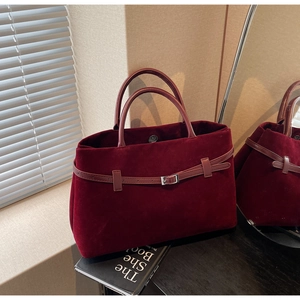 Close-up of burgundy velvet tote bag with leather straps and silver buckle detail