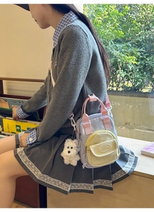 Girl wearing a small purple and pink nylon crossbody bag with a white puppy plush charm