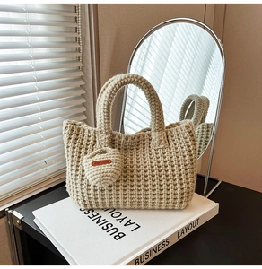 Close-up of beige knit tote bag with thick texture and Hand Made leather tag charm