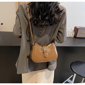 Detailed view of brown glossy leather crossbody bag with silver square metal buckle