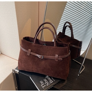 Macro detail of dark brown matte suede texture and metal buckle on the vintage tote bag