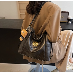 Close-up of vintage black PU leather tote bag with gold M logo and bear charm