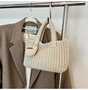 Close-up of cream knit tote bag with matching mini coin purse on a metal hanger