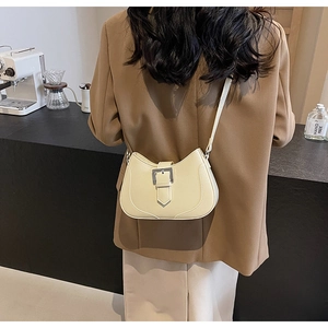 Detail of cream half-moon crossbody bag with large silver buckle and smooth leather finish
