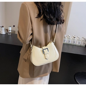Model wearing a chic beige saddle bag with a metal buckle over a brown blazer