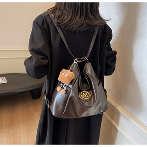 Close-up of vintage brown tote bag with metallic M logo and plush bear charm