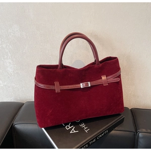 Detail of burgundy velvet tote bag featuring a leather strap with silver metal buckle