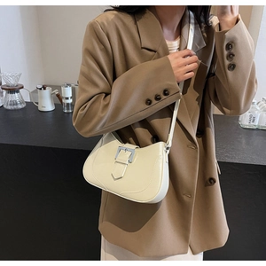 Chic beige crescent bag with silver buckle worn by a model in a casual urban setting