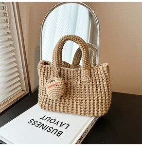 Close-up of khaki crochet bucket bag texture with a heart-shaped Hand Made charm