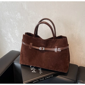 Detailed close-up of dark brown matte leather tote bag with silver metal buckle detail