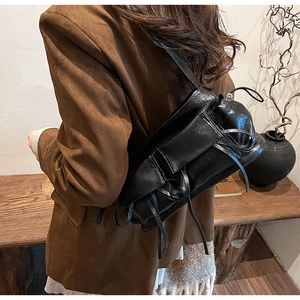 Detail of black pleated shoulder bag with bow accents and drawstring in vintage style