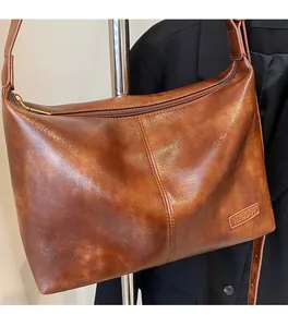 Détail du sac bandoulière vintage en cuir ciré marron foncé avec fermeture éclair et logo