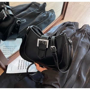 Detail of black glossy PU leather crescent bag with silver buckle and mirror reflections