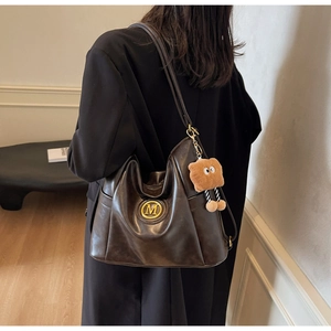 Deep brown large hobo bag with gold M logo and cute bear charm shown on model
