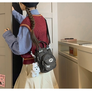 Detail of dark grey mini canvas crossbody bag with cute white plush dog keychain
