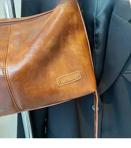 Gros plan du sac en cuir marron vintage avec texture litchi et logo NIJNOMM